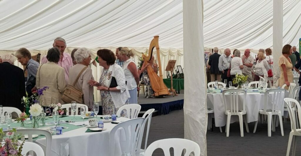 RCC 20th Anniversary fundraiser event - showing table settings, harpist and guests greeting each other in the marquee at Old Buckenham Hall