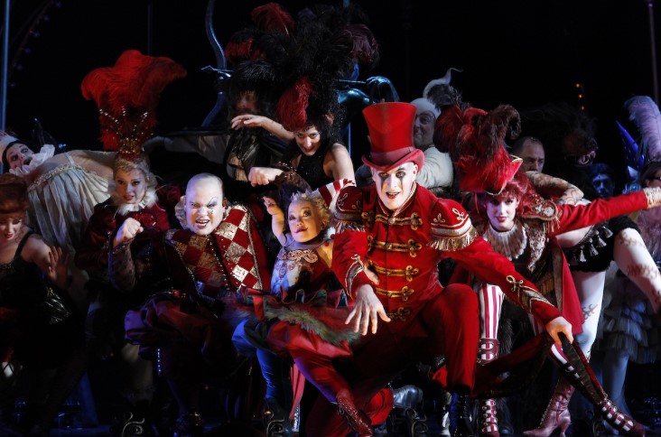 Photo of cast of 2011 performance of Love Never Dies in grouped together on stage in full red and white circus style theatrical costume