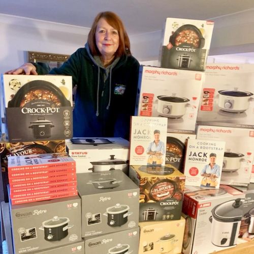 Photo of Ann stood with a stack of boxed slow cookers