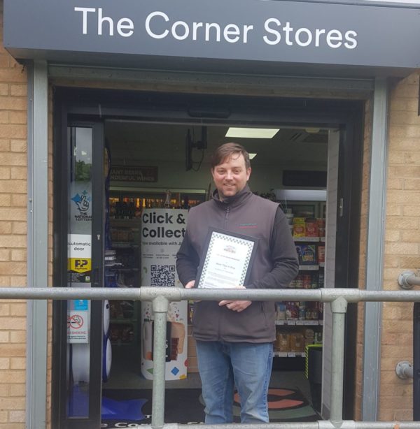 The Corner Stores Mildenahll receiving their More Than A Shop Award Corner Stores Mildenhall shop front and owner with More Than A Shop Certificate