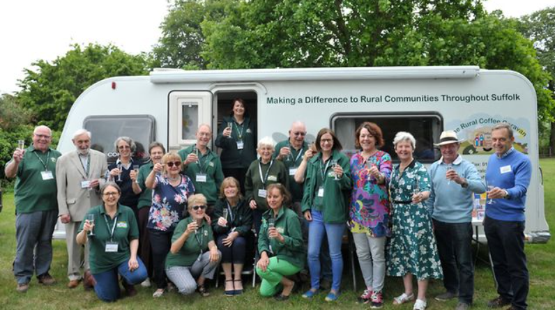 photo of staff and trustees of the rural Coffee caravan celebrating their award in front of the charity's caravan