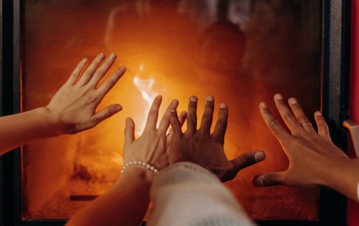 photo of people's hands stretched out to warm them in front of a fireplace